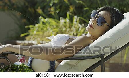 Profile view of woman in sunglasses and bikini sunbathing and laying on lawn chair View Large Photo Image Stock Image - Profile view of woman in sunglasses and bikini sunbathing and laying on lawn chair. Fotosearch