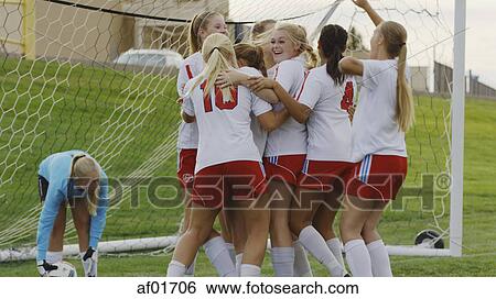 Stock Photograph - Proud athlete with soccer teammate cheering after game victory in goal. Fotosearch