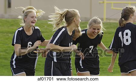 Stock Image - Proud athlete with soccer teammates cheering after game victory on field. Fotosearch