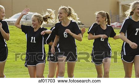 Stock Image - Proud athlete with soccer teammates cheering after game victory on field. Fotosearch