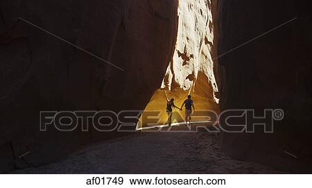 Rear view of silhouette of boyfriend and girlfriend exploring cave in scenic rock formations View Large Photo Image Stock Photo - Rear view of silhouette of boyfriend and girlfriend exploring cave in scenic rock formations. Fotosearch