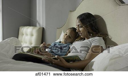 Relaxing mother and son reading book on bed View Large Photo Image Stock Image - Relaxing mother and son reading book on bed. Fotosearch
