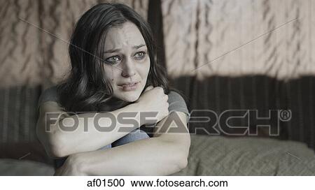 Sad battered woman holding her knees and crying on bed View Large Photo Image Stock Image - Sad battered woman holding her knees and crying on bed. Fotosearch