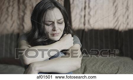Sad battered woman holding her knees and crying on bed View Large Photo Image Stock Image - Sad battered woman holding her knees and crying on bed. Fotosearch