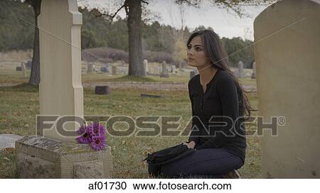 Sad pensive woman sitting at grave in lonely cemetery View Large Photo Image Stock Image - Sad pensive woman sitting at grave in lonely cemetery. Fotosearch
