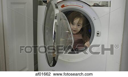 Selective focus close up of exploring playful girl hiding in washing machine View Large Photo Image Stock Image - Selective focus close up of exploring playful girl hiding in washing machine. Fotosearch