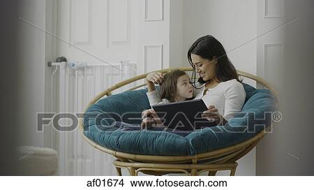 Selective focus view of mother and daughter using digital tablet and sitting in chair View Large Photo Image Picture - Selective focus view of mother and daughter using digital tablet and sitting in chair. Fotosearch