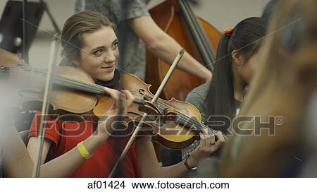 Picture - Selective focus view of serious teenage girl musician playing violin in band class. Fotosearch