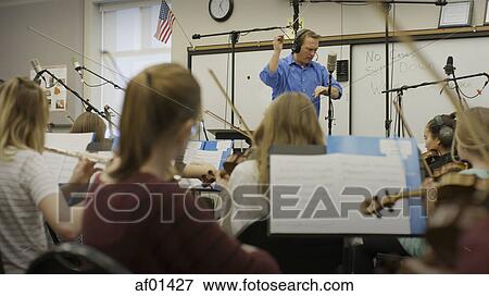 Stock Photo - Selective focus view of teacher conducting musicians in band class. Fotosearch