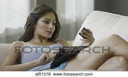 Selective focus view of woman shopping online with credit card and digital tablet on sofa View Large Photo Image Stock Photo - Selective focus view of woman shopping online with credit card and digital tablet on sofa. Fotosearch
