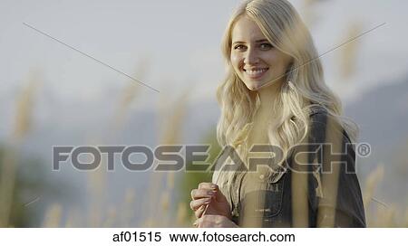 Selective focus view of woman smiling in grass in remote landscape View Large Photo Image Stock Photography - Selective focus view of woman smiling in grass in remote landscape. Fotosearch