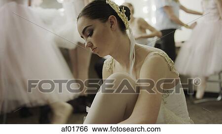 Stock Photograph - Serious ballet dancer in costume stretching backstage before show. Fotosearch