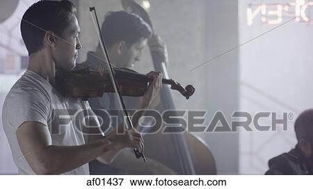 Serious musician playing violin in band in cafe View Large Photo Image Stock Photo - Serious musician playing violin in band in cafe. Fotosearch
