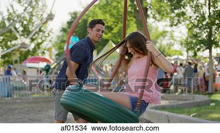 Side view of laughing happy boyfriend pushing blurred girlfriend on tire swing in park View Large Photo Image Picture - Side view of laughing happy boyfriend pushing blurred girlfriend on tire swing in park. Fotosearch