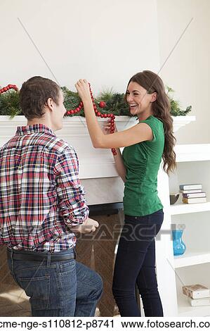 Stock Image - Smiling couple decorating room for Christmas. Fotosearch