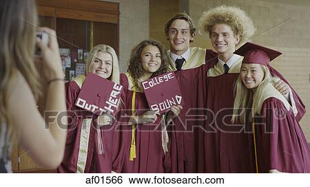 Smiling Students Posing With Decorated Mortarboards At Graduation