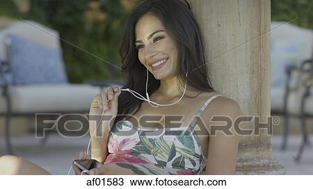 Stock Image - Smiling woman in swimsuit listening to headphones and mp3 player. Fotosearch