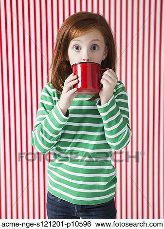 Stock Photograph - Studio portrait of girl (4-5) drinking from red mug. Fotosearch