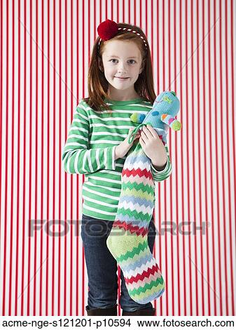 Picture - Studio portrait of girl (4-5) holding Christmas stocking. Fotosearch