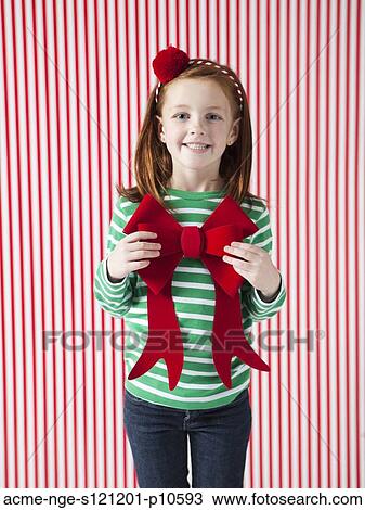 Studio portrait of girl (4-5) holding Christmas bow View Large Photo Image Stock Image - Studio portrait of girl (4-5) holding Christmas bow. Fotosearch