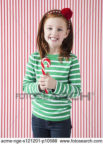Stock Photo - Studio portrait of girl (4-5) holding candy cane. Fotosearch