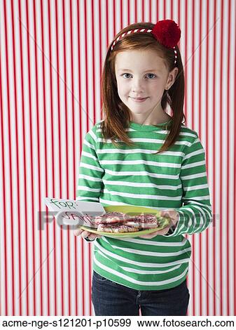 Stock Photo - Studio portrait of girl (4-5) holding letter to Santa and cookies. Fotosearch
