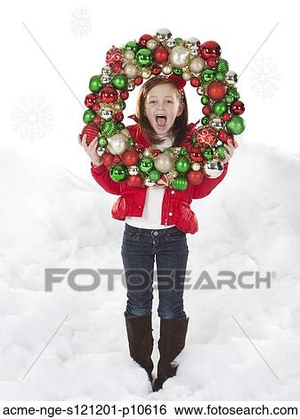 Stock Photograph - Studio portrait of girl (4-5) holding Christmas decoration. Fotosearch