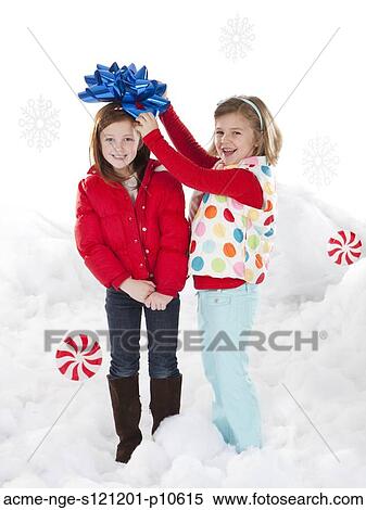 Stock Photography - Studio portrait of girls (4-5, 6-7) standing in snow. Fotosearch