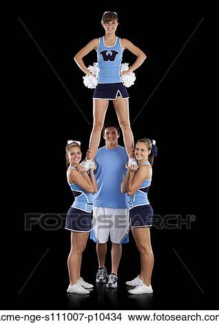 Studio shot of cheerleaders (16-17) assisting friend during performance View Large Photo Image Picture - Studio shot of cheerleaders (16-17) assisting friend during performance. Fotosearch