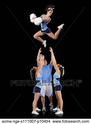 Studio shot of cheerleaders (16-17) assisting friend during jump View Large Photo Image Picture - Studio shot of cheerleaders (16-17) assisting friend during jump. Fotosearch