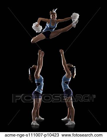 Studio shot of cheerleaders (16-17) assisting friend during jump View Large Photo Image Stock Image - Studio shot of cheerleaders (16-17) assisting friend during jump. Fotosearch