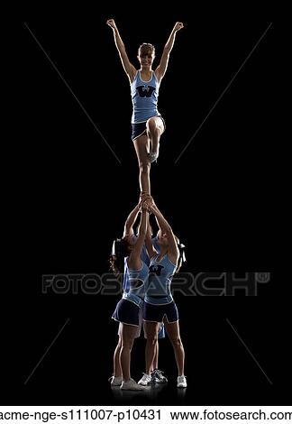 Studio shot of cheerleaders (16-17) supporting friend standing on one leg View Large Photo Image Stock Image - Studio shot of cheerleaders (16-17) supporting friend standing on one leg. Fotosearch