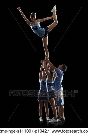 Studio shot of cheerleaders (16-17) supporting friend standing on one leg View Large Photo Image Stock Photo - Studio shot of cheerleaders (16-17) supporting friend standing on one leg. Fotosearch