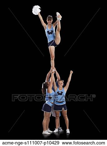 Stock Photo - Studio shot of cheerleaders (16-17) supporting friend standing on one leg. Fotosearch
