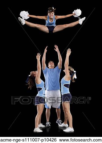 Studio shot of cheerleaders (16-17) assisting friend during jump View Large Photo Image Stock Photograph - Studio shot of cheerleaders (16-17) assisting friend during jump. Fotosearch