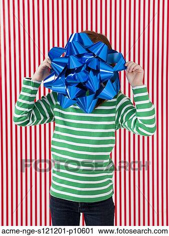 Studio shot of girl (4-5) holding large gift bow in front of face View Large Photo Image Stock Image - Studio shot of girl (4-5) holding large gift bow in front of face. Fotosearch