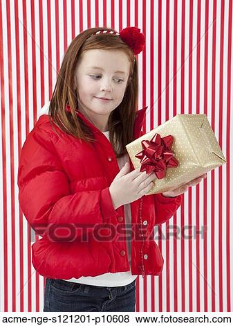 Stock Photo - Studio shot of girl (4-5) holding of Christmas gift. Fotosearch