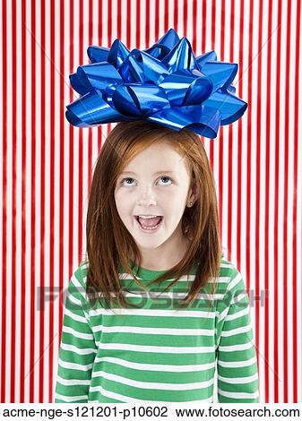 Stock Image - Studio shot of girl (4-5) with large gift bow on head. Fotosearch