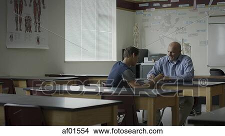 Picture - Teacher instructing and tutoring student in classroom. Fotosearch