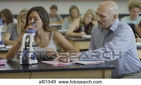 Teacher instructing student using microscope for scientific experiment in science lab classroom View Large Photo Image Stock Photo - Teacher instructing student using microscope for scientific experiment in science lab classroom. Fotosearch