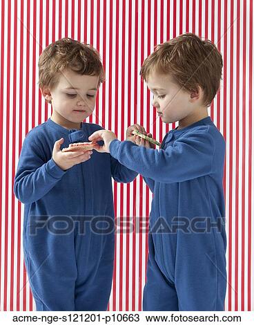 Twin boys (2-3) wearing pajamas holding gingerbreads View Large Photo Image Stock Image - Twin boys (2-3) wearing pajamas holding gingerbreads. Fotosearch