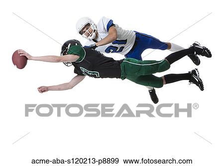 Stock Photo - Two male players of American football fighting for ball, studio shot. Fotosearch