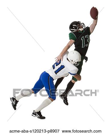 Stock Photo - Two male players of American football fighting for ball, studio shot. Fotosearch