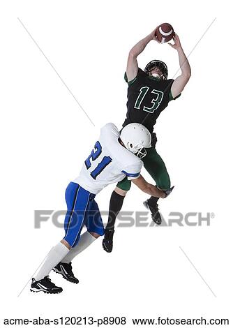 Stock Photo - Two male players of American football fighting for ball, studio shot. Fotosearch