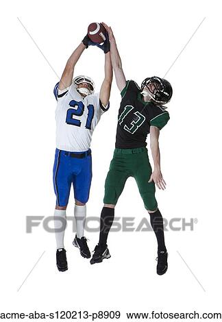 Stock Photo - Two male players of American football catching ball, studio shot. Fotosearch