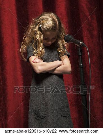 Stock Image - USA, Utah, Orem, Portrait of girl (8-9) with arms crossed standing in front of microphone. Fotosearch