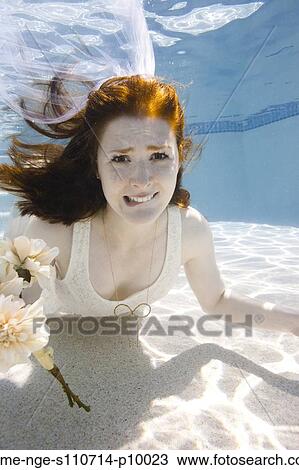 Stock Image - USA, Utah, Orem, Portrait of young bride with bouquet under water. Fotosearch