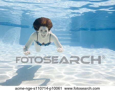 Stock Image - USA, Utah, Orem, Smiling woman swimming in swimming pool. Fotosearch