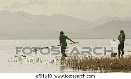 Volunteers collecting recycling and trash garbage on remote grassy lake shore View Large Photo Image Stock Image - Volunteers collecting recycling and trash garbage on remote grassy lake shore. Fotosearch
