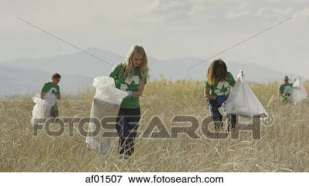 Volunteers collecting recycling and trash garbage on remote grassy beach View Large Photo Image Stock Photo - Volunteers collecting recycling and trash garbage on remote grassy beach. Fotosearch